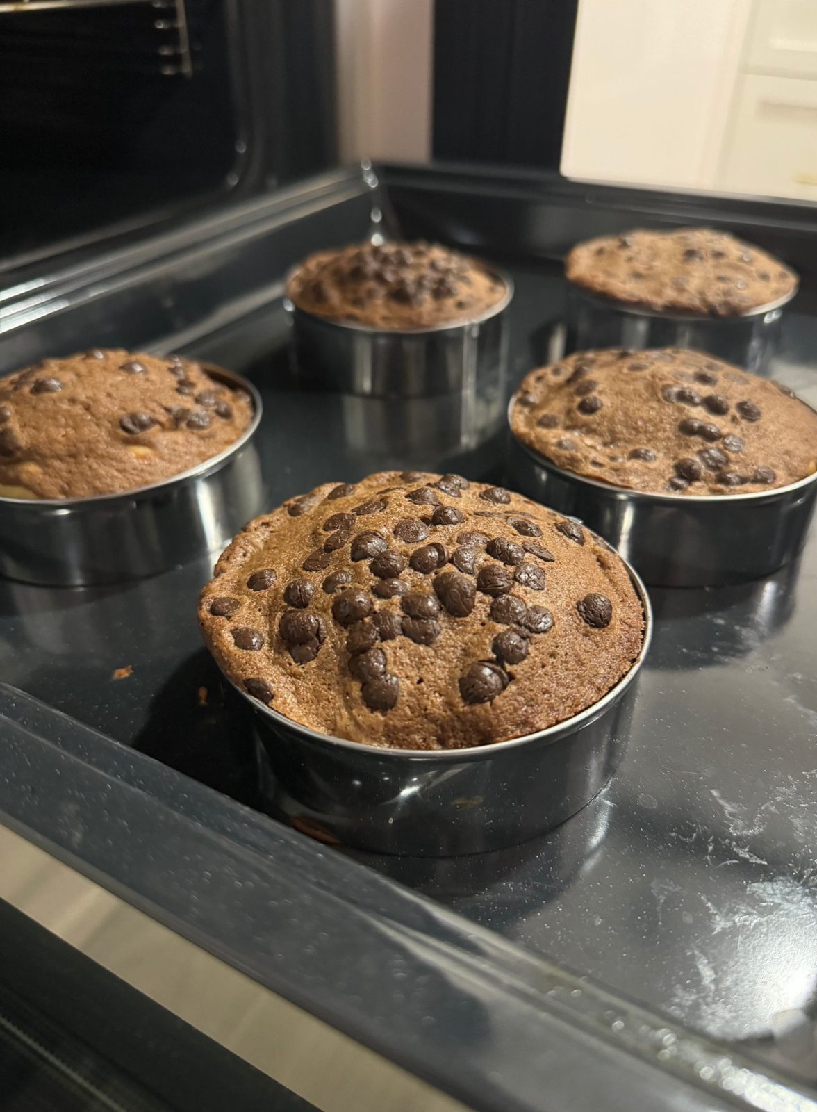 Chocolate chip cakes baked in ring moulds, on an oven tray