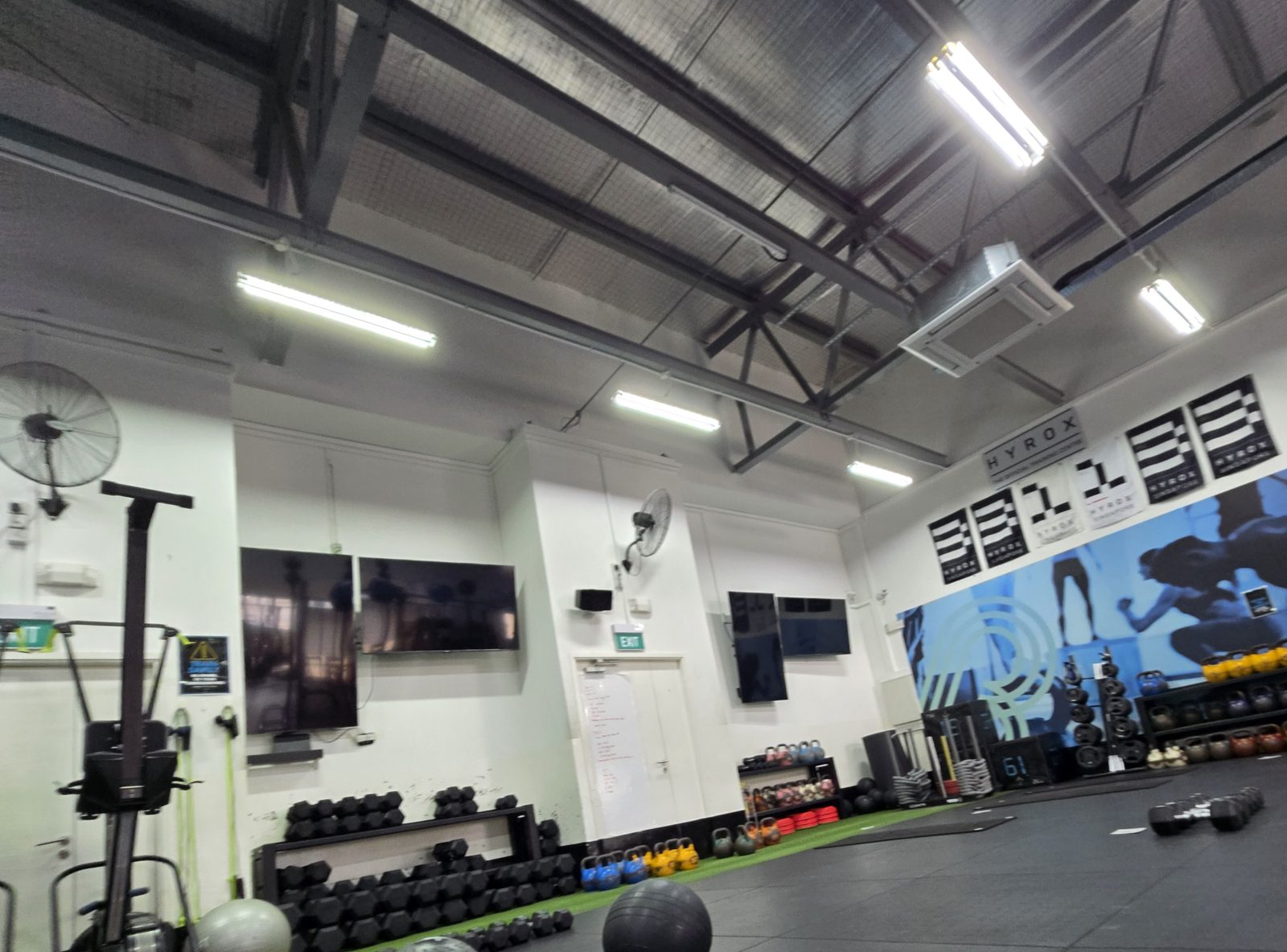A training gym floor with slam balls, dumbbells and kettlebells