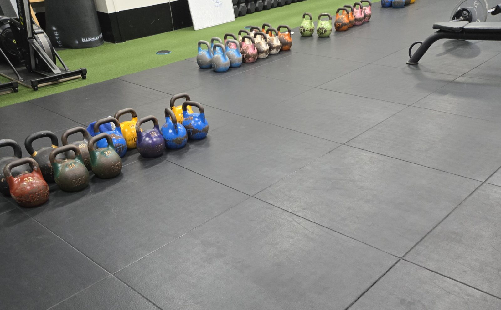 Rows of coloured kettlebells on rubber flooring
